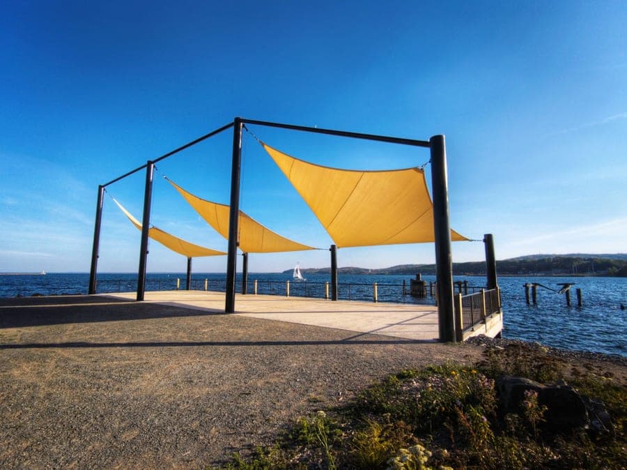 Heavy-duty shade sail with a reinforced cable edge tensioned over a patio with metal posts